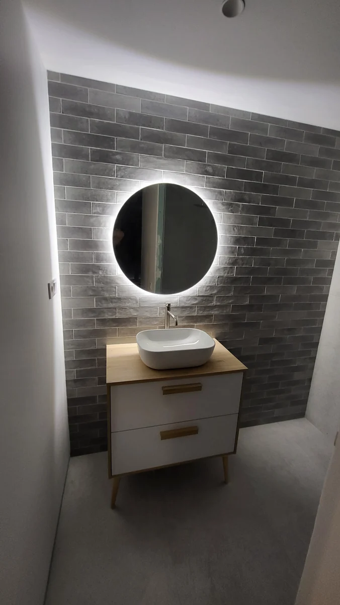 Lavabo sobre moble de fusta i mirall rodó retroil·luminat