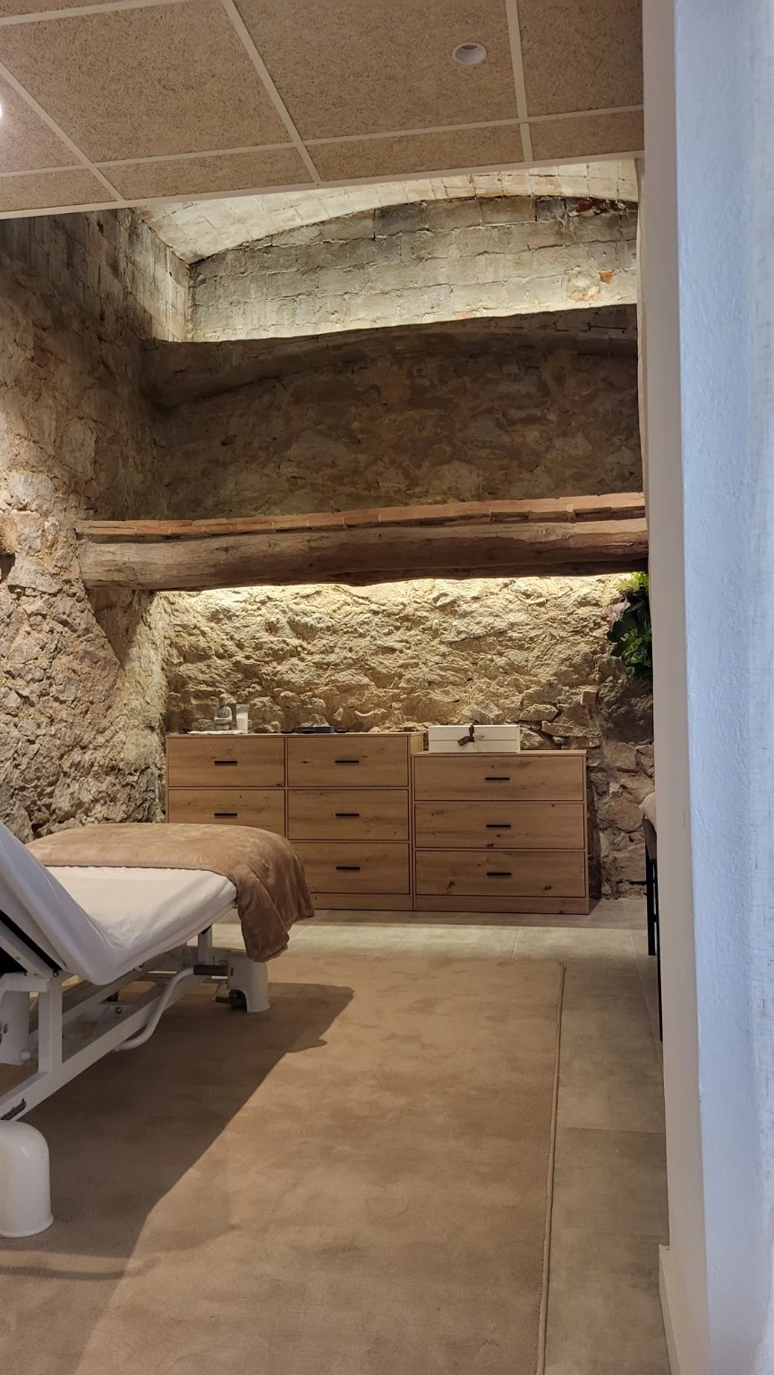 Sala de tractaments amb parets de pedra i il·luminació indirecta sobre les bigues
